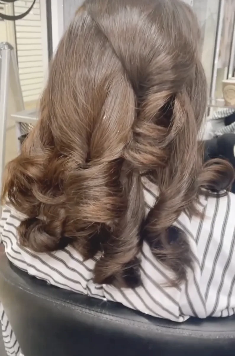 Bridal half-up brunette updo with soft barrel curls, seen from behind