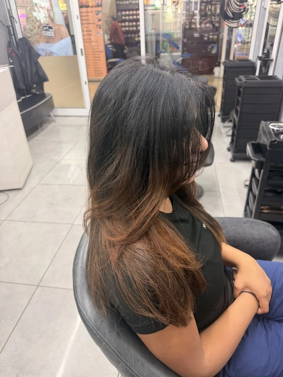 Long dark hair with a warm caramel balayage falling over the shoulder