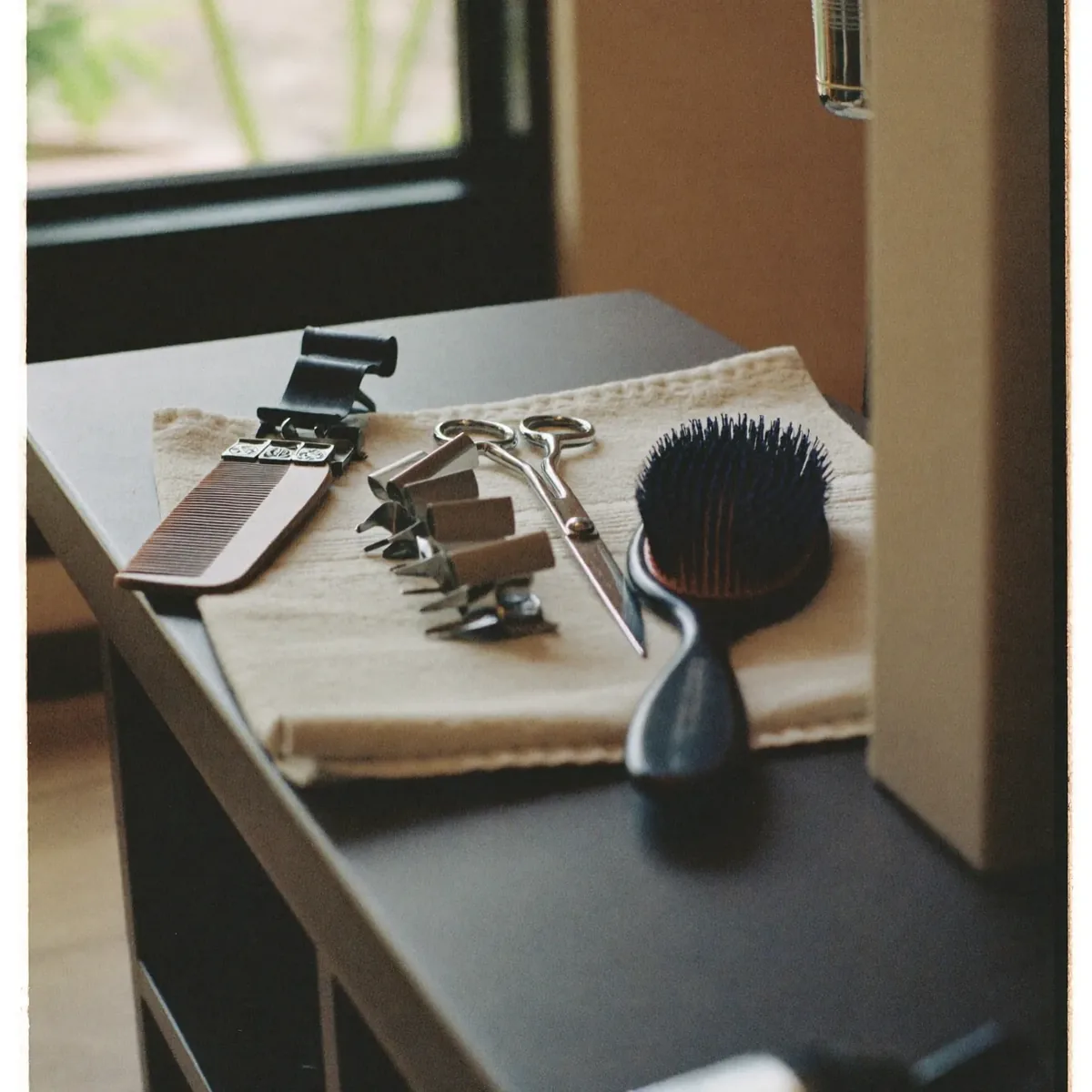 Scissors, brushes, clips and a comb laid out on a salon styling counter